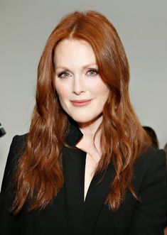 a woman with long red hair wearing a black suit