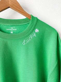 Maybe it's the luck of the Irish! This design is embroidered on a festive green crewneck sweatshirt with white thread for festive, holiday apparel! It is unisex sized. This means the sizing is boxy, not fitted like women's, but it is not oversized. It is true to size. This design is not customizable. This design and colors cannot be altered, resized, or changed. Specifications: 8 oz.(US) 13.3 oz.(CA), 50/50 preshrunk cotton/polyester Heather Sport colors: 60/40 polyester/cotton Air jet yarn = so Green Crew Neck Sweatshirt With Embroidered Text, Green Long Sleeve Sweater With Embroidered Text, Green Crew Neck Top With Letter Embroidery, Green Embroidered Crew Neck Sweater, Green Crew Neck Sweatshirt With Letter Embroidery, Green Embroidered Text Sweatshirt For Winter, Reality Shifting, Custom Crewneck Sweatshirts, Lucky Leaf