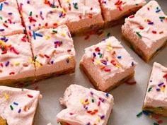 there are many pieces of cake with pink frosting and sprinkles on it