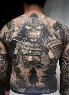 the back of a man's body with tattoos on it, including an image of samurai