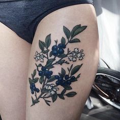 a woman's thigh with flowers and leaves on it