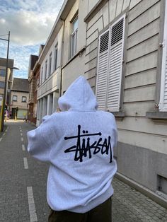 a person in a white hoodie is walking down the street with their back to the camera