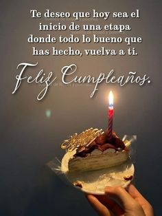 a person holding a piece of cake with a lit candle on it and the words feliz cumpleanos written in spanish