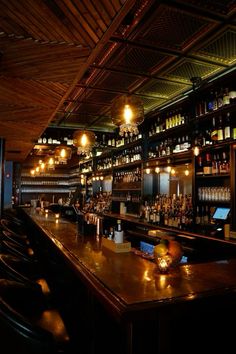 a dimly lit bar with lots of bottles on the shelves and lights hanging from the ceiling