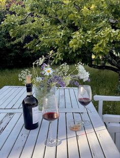 two wine glasses sitting on top of a wooden table next to a bottle of wine