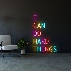 a neon sign that says i can do hard things next to a chair and potted plant