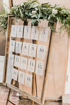 an easel with seating cards and greenery on it