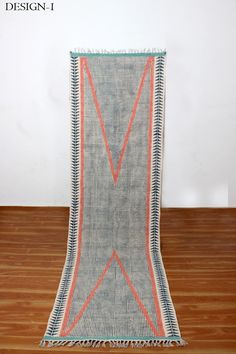 a blue and orange rug with fringes on top of a wooden floor next to a white wall