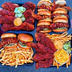 several trays filled with different types of food including hot dogs, fries and burgers