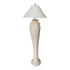 a white lamp with a beige shade on it's base and a light bulb in the shape of a vase