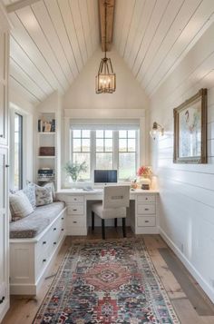 a white room with a rug, desk and window in the corner on the floor