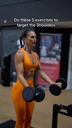 a woman in an orange outfit holding two black dumbbells