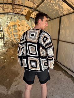 a man standing in front of a white and black crocheted jacket with circles on it