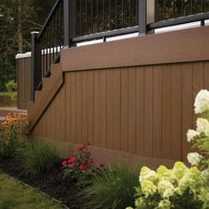 a wooden fence with flowers and bushes around it