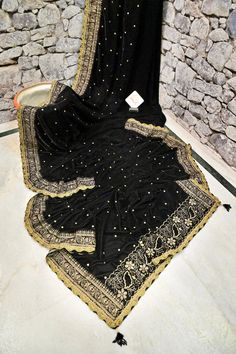 Be the one to shop this designer velvet look first with IndyVogue. Made with soft velvet fabric, it features intricate zari embroidery all over, created using a special machine. The lace border is adorned with delicate mirrorwork, and the pallu has tassels hanging from it. Elevate your ethnic wardrobe with this unique and luxurious saree. Color: A shade of black color Technique: An enriching work of zari embroidery with a lace border with mirror work and tassels on the pallu. Fabric: Velvet Velvet Traditional Wear For Diwali, Festive Velvet Saree Set, Festive Velvet Saree, Festive Velvet Traditional Wear With Traditional Drape, Velvet Saree Set With Zari Work, Elegant Velvet Saree With Pallu, Velvet Traditional Drape For Diwali, Bollywood Velvet Saree With Zari Work, Velvet Saree With Zari Work And Traditional Drape