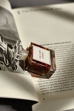 a bottle of perfume sitting on top of an open book