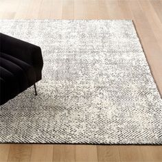 a black chair sitting on top of a wooden floor next to a white and black rug