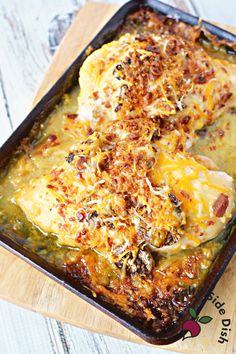 a casserole dish with meat and cheese in it on a wooden cutting board