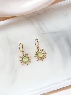 A Beautiful and cute pair of sunflower earrings that are a lovely lime light green opal cats eye effect to give them that shine, on a lever back stainless steel gold coloured hook, very stylish and pretty and great for a summer vibe. I think these earrings are very cute and stylish, they give off a lot of shine in the light so they would look really pretty out in the sun with a summers dress. These earrings are nice and light in weight so they will not feel too much of a burden wearing them for a long time. MATERIALS: The earring leverbacks are made from stainless steel which is hypo-allergenic, which means decreased tendency to cause an allergic reaction. HOW TO CARE FOR YOUR JEWELLERY To keep jewellery looking fresh and extend its lifespan it is recommended to: - Remove jewellery before Green Earrings For Summer Gift, Green Hypoallergenic Earrings For Summer, Summer Green Hypoallergenic Earrings, Summer Green Nickel-free Earrings, Lime Green Earrings For Gift, Dainty Green Summer Jewelry, Green Hoop Earrings, Summer Gift, Green Hoop Earrings For Summer, Green Hoop Earrings As Summer Gift