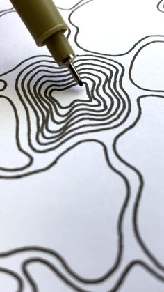 a pen is writing on a piece of paper with an abstract pattern in the background