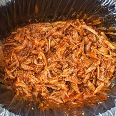 shredded meat in a foil container on top of a tableclothed surface, ready to be cooked