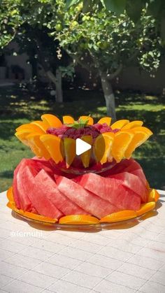 a watermelon and orange cake on a table in front of some trees,