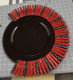 a black plate with red and white designs on it sitting on a cutting board next to scissors