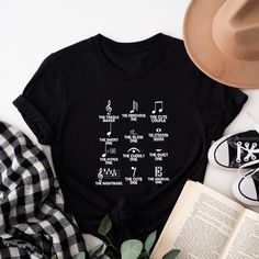 a t - shirt with musical notes on it next to a hat and an open book