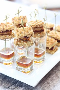 small desserts are arranged in individual cups on a white plate with toothpicks sticking out of them