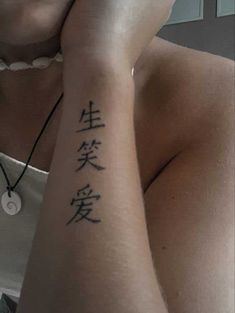 a woman is holding her hand up to her face with chinese writing on the wrist