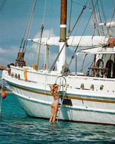 a woman standing in the water next to a boat