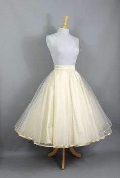 "This show stopping bridal skirt is made from a layer of Champagne Silk Dupion and a layer of ivory tulle hemmed in Gold trim. The tulle layer is a double circle which means lots and lots of volume! Wear with a 'Swing' petticoat for extra swish on the dance floor (or seen in the last photo without a petticoat underneath) and choose your length to create a unique outfit for your special day. Off-the-peg in a size  UK 16 (US 14/EU 44). It has been made to fit a waist measurement of 33-34\" (83-87c Gold Champagne Bridesmaid Skirt, Double Citcle Skirt, Champagne Wedding Skirt, Wedding Tea Length Dress With Tulle Skirt, Fitted Full Tulle Petticoat, Fitted Full Tulle Skirt Petticoat, Wedding Tulle Petticoat, Voluminous Tulle Skirt For Wedding, Elegant Organza Petticoat With Tulle Skirt