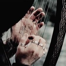 a man holding an instrument in his hands with celtic designs on the strings and wristbands