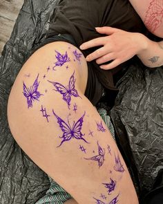 a woman laying on top of a bed covered in purple butterflies and stars painted on her leg