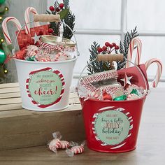 two buckets filled with candy and candies on top of a wooden table next to a christmas tree