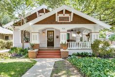 a small white house with brown trim on the front porch and steps leading up to it