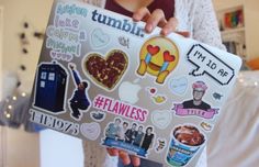 a woman holding up a laptop covered in stickers