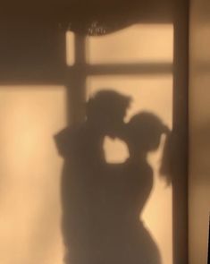 the shadow of two people standing in front of a window with their arms around each other