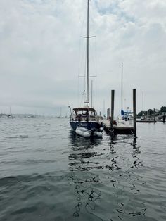 a sailboat docked at a pier on the water with other boats in the background