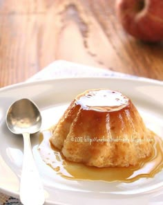 a small pastry on a plate with caramel sauce and an apple in the background