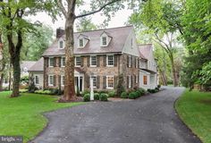 a large brick house with lots of windows and trees in the front yard on a cloudy day