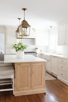 a kitchen with white cabinets and an island that has baskets on top of it in front of the sink