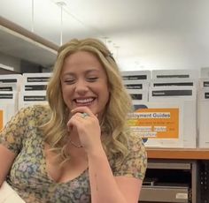 a woman sitting at a desk smiling and holding a piece of paper in her hand