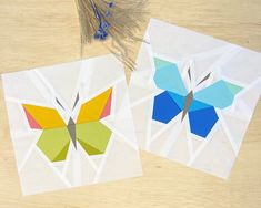 two paper butterflies sitting on top of a wooden table