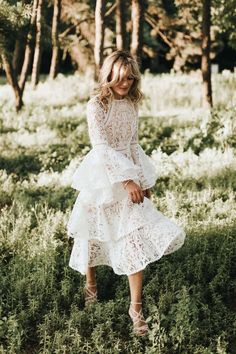 a woman in a white dress is standing in the grass