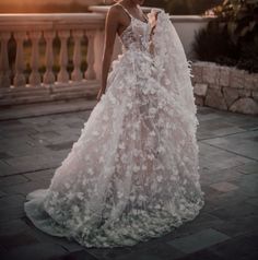 a woman in a wedding dress is standing on a balcony with her back to the camera