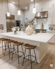 a kitchen island with four stools in front of it and a vase on the counter