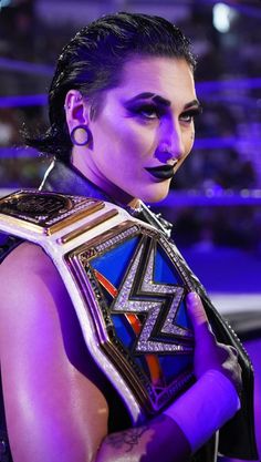 a woman with purple makeup holding a wrestling belt