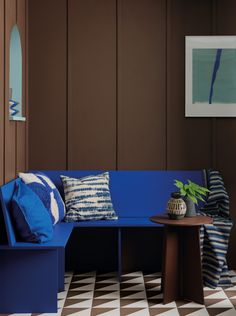 a blue bench sitting in the middle of a room next to a table with two vases on it