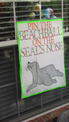 a sign posted on the side of a window that says pin the beach ball on the seal's nose